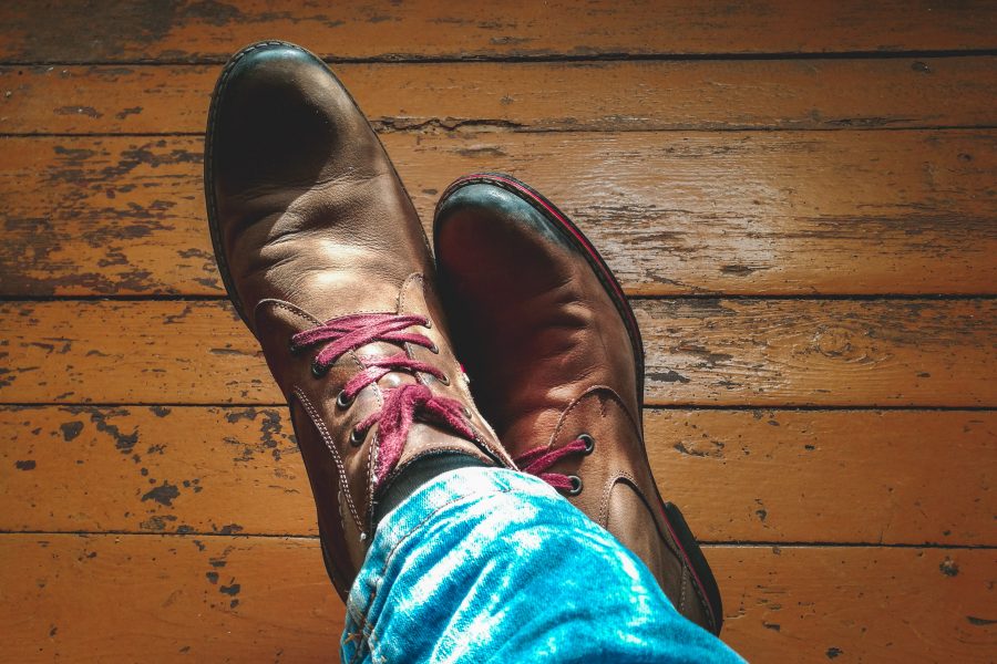 Skórzane brązowe buty wiązane na nogach kogoś ubranego w jeansy